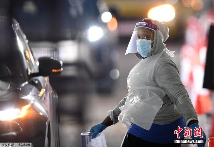 當(dāng)?shù)貢r間12月18日，英國政府公布的數(shù)據(jù)顯示，當(dāng)天英國新增奧密克戎毒株感染病例10059例。鑒于奧密克戎毒株感染病例激增，住院人數(shù)不斷上升，倫敦市長宣布倫敦進(jìn)入“重大事故”狀態(tài)。圖為倫敦的一個免下車檢測中心，一名醫(yī)務(wù)工作者正準(zhǔn)備對司機(jī)進(jìn)行核酸檢測。