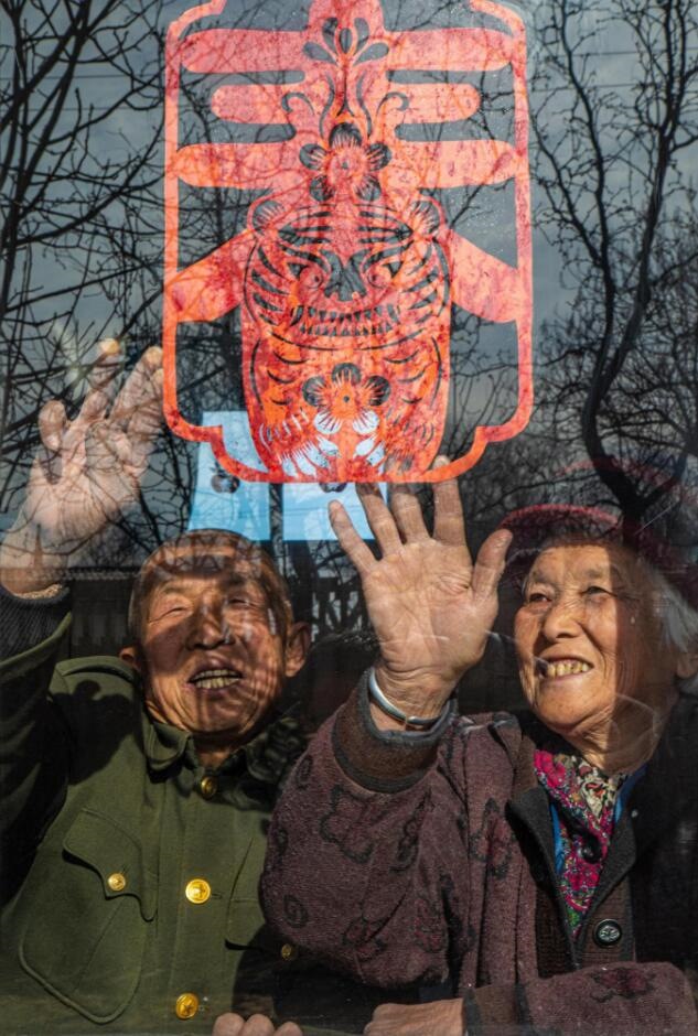 臘月里，霍州市師莊鄉(xiāng)馮南垣村村民師榮光(左)在災(zāi)后重建的新家里貼窗花。(霍州市委宣傳部供圖)