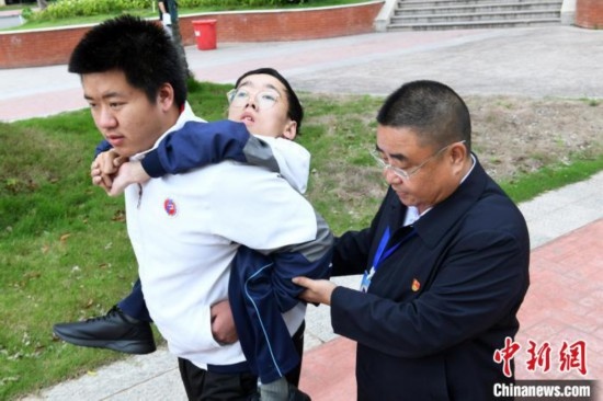 朱金祥背著鐘華強去教室上課的路上，也經(jīng)常碰到值班的校領(lǐng)導(dǎo)和老師前來搭把手。 卓忠偉 攝