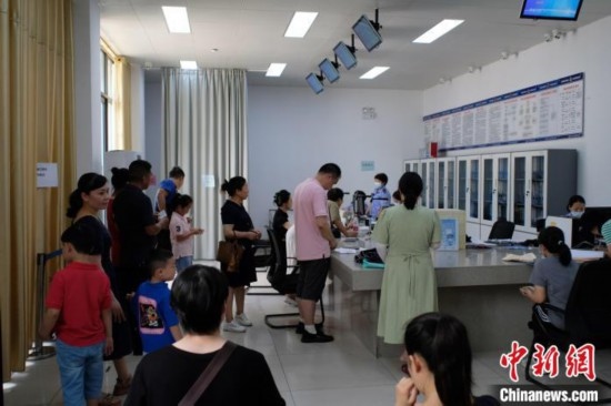 圖為在戶籍辦證廳內(nèi)排隊(duì)等待的家長和孩子。劉俊聰 攝