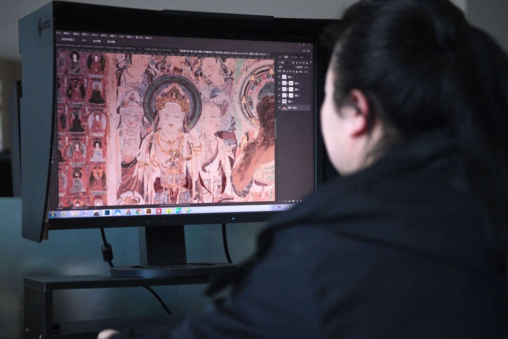 敦煌研究院文物數(shù)字化保護(hù)團(tuán)隊(duì)圖像處理人員年海麗在拼接壁畫圖像（2023年4月25日攝）。數(shù)字化探索為莫高窟的保護(hù)與傳承開辟了全新路徑，數(shù)字技術(shù)讓敦煌文物走出洞窟，跨出國門，走向“永久保存、永續(xù)利用”。新華社記者 陳斌 攝