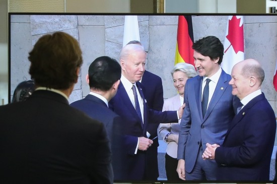 2022年3月24日，在比利時(shí)布魯塞爾的北約總部，一名男子觀看屏幕上美國總統(tǒng)拜登（右四）、歐盟委員會(huì)主席馮德萊恩（右三）、加拿大總理特魯多（右二）、德國總理朔爾茨（右一）出席七國集團(tuán)峰會(huì)合影儀式的畫面。新華社記者鄭煥松攝