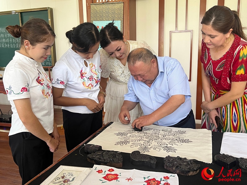 國(guó)家級(jí)非物質(zhì)文化遺產(chǎn)模戳印花布技藝傳承人吾吉阿西木?吾舒爾展示模戳印花布的制作過(guò)程。人民網(wǎng)記者 常雪梅攝