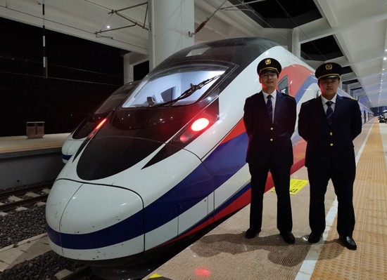 劉銀能（右一）與中國(guó)師父鄔俊鴻在動(dòng)車組前合影。受訪者供圖