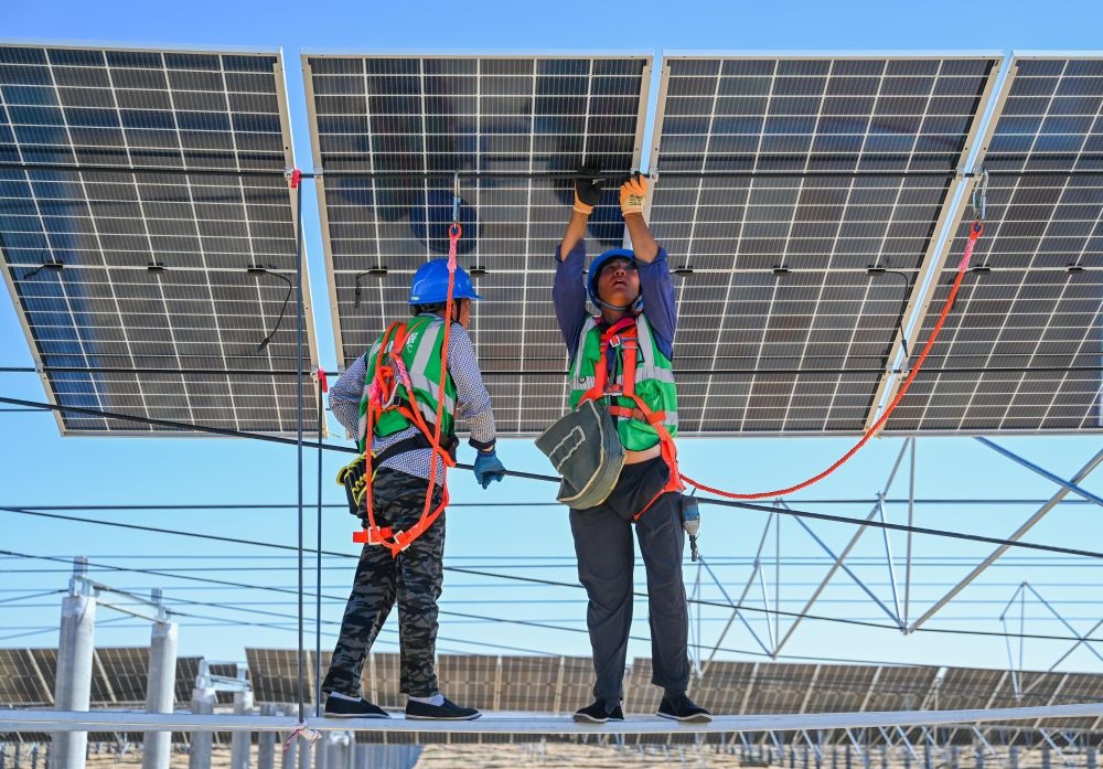2023年7月22日，工人在位于內(nèi)蒙古杭錦旗庫布其沙漠億利生態(tài)示范區(qū)的蒙西基地庫布其200萬千瓦光伏治沙項(xiàng)目工地安裝光伏板。新華社記者 劉磊 攝