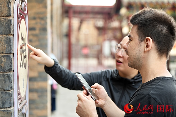 選手安德烈（俄羅斯）在老師指導(dǎo)下學(xué)習(xí)墻壁上張貼的生僻字。人民網(wǎng) 盧鵬宇攝