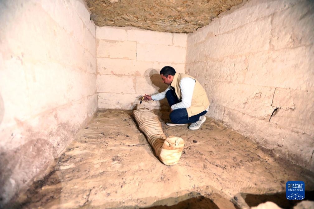 10月15日，在埃及明亞省考古現(xiàn)場，考古人員清理一座石鑿墓中的木乃伊。新華社發(fā)（艾哈邁德·戈馬攝）