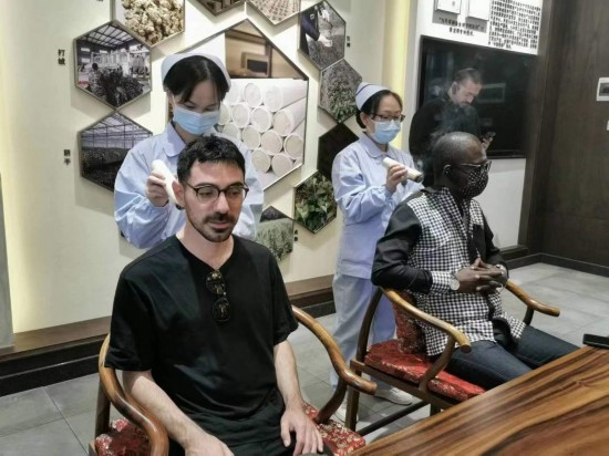 2023“一帶一路”媒體合作論壇聯(lián)合采訪團團員在九牛草展示館體驗艾灸。（本報記者 黃超攝）