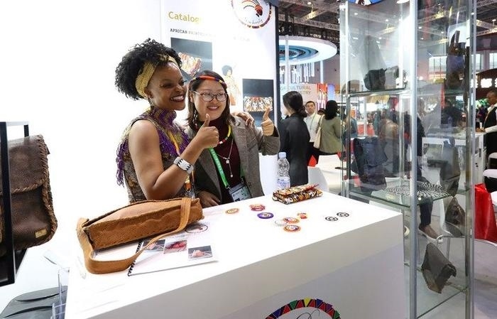 11月6日，一位參觀者（右）在第六屆進(jìn)博會(huì)國(guó)家展南非展臺(tái)試戴傳統(tǒng)首飾。