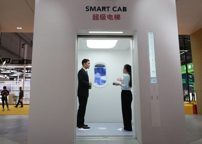 11月5日，工作人員（右）在第六屆進(jìn)博會(huì)上向參觀者介紹奧的斯公司全新推出的超級(jí)電梯。