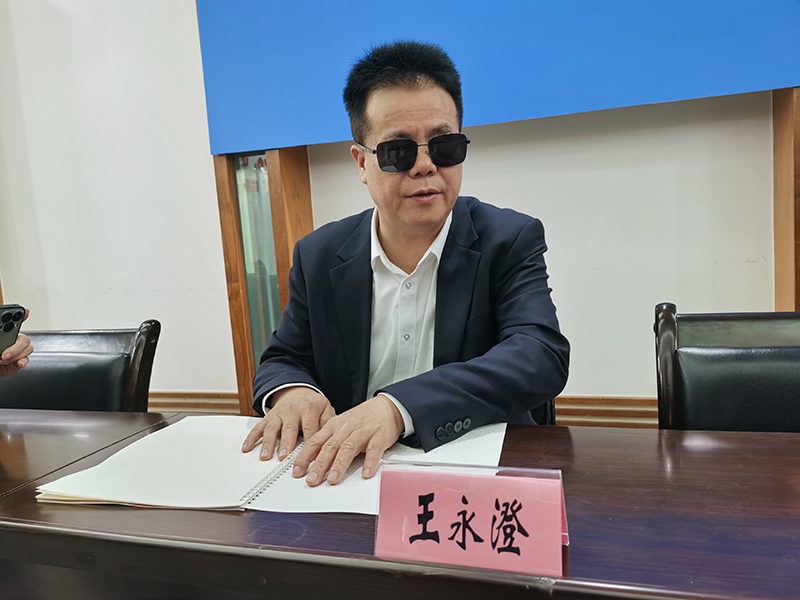 全國人大代表王永澄正在閱讀盲文版代表建議答復(fù)。本報記者 張 璁?dāng)z