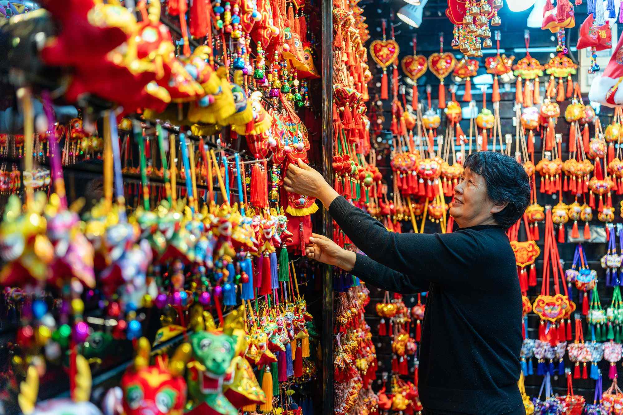 2023年12月11日，金華義烏國際商貿(mào)城，龍年喜慶用品掛滿攤位，顧客正在挑選中。