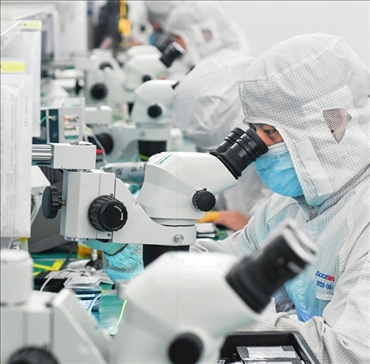 在位于武漢中國(guó)光谷的光電器件研發(fā)制造商——武漢光迅科技股份有限公司生產(chǎn)車間內(nèi)，技術(shù)人員在光模塊生產(chǎn)線作業(yè)（2023年4月11日攝）。程敏攝/本刊