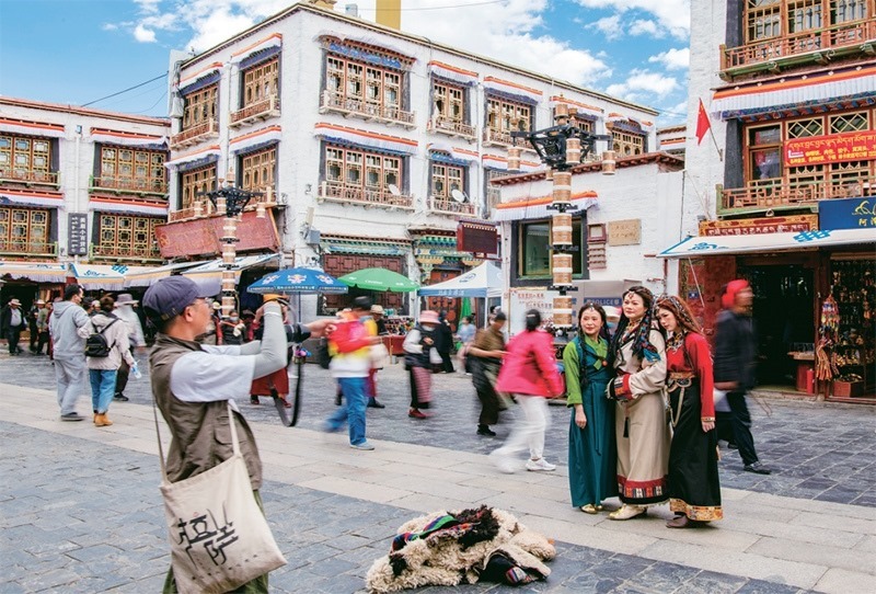 千年八廓街，見(jiàn)證民族團(tuán)結(jié)。2021年7月，習(xí)近平總書(shū)記來(lái)到位于西藏拉薩老城區(qū)的八廓街，感慨地說(shuō)：“千年八廓街，是我們各民族建起來(lái)的八廓街。各民族文化在這里交流交往交融，我們中華民族的大家庭在這里其樂(lè)融融?！眻D為2023年6月13日，游客身著藏裝在八廓街拍照留念。 新華社記者 姜帆/攝