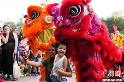 圖為舞獅表演吸引民眾合影。張興龍攝