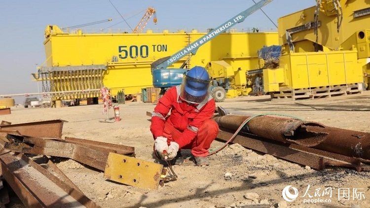 工人正在龍門吊吊裝現(xiàn)場切割金屬件。人民網(wǎng)記者管克江攝