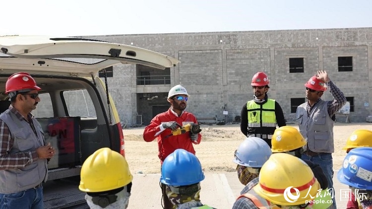 穆薩瓦爾(圖中紅衣人）現(xiàn)場演示工具操作規(guī)范。人民網(wǎng)記者 管克江攝