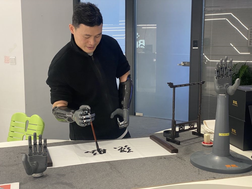 2024年3月29日，在浙江強(qiáng)腦科技有限公司展廳內(nèi)，失去雙手的產(chǎn)品體驗(yàn)官倪敏成依靠智能仿生手寫(xiě)毛筆字。新華社記者 魏一駿 攝