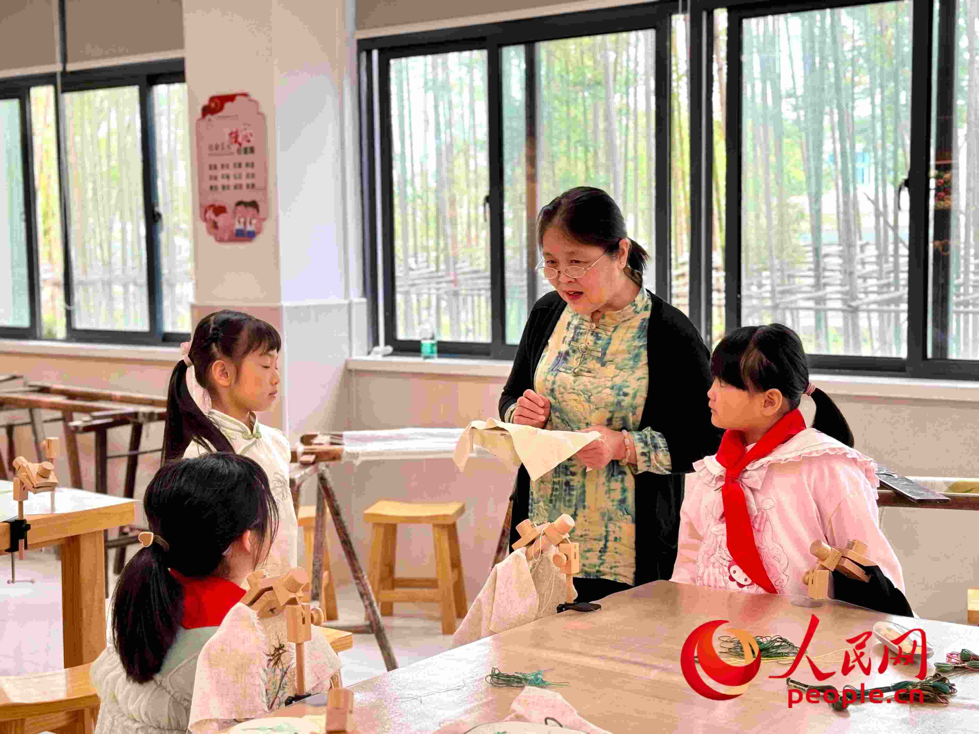 顧建珍（左三）在教孩子們刺繡知識(shí)。人民網(wǎng) 周靜圓攝
