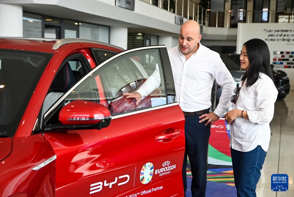 2024年5月29日，在馬耳他比爾基卡拉，馬耳他哈桑-扎米特汽車公司首席執(zhí)行官德古阿拉（左）介紹一輛比亞迪純電動汽車。新華社發(fā)（喬納森·博格 攝）