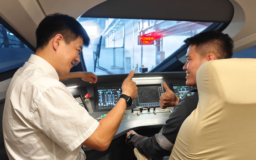 2023年8月25日，在印度尼西亞萬隆的雅萬高鐵德卡魯爾動(dòng)車所內(nèi)，中國師傅穆振（左）向印尼火車司機(jī)塞蒂亞萬講解動(dòng)車組出庫前的上電作業(yè)。新華社記者 徐欽 攝