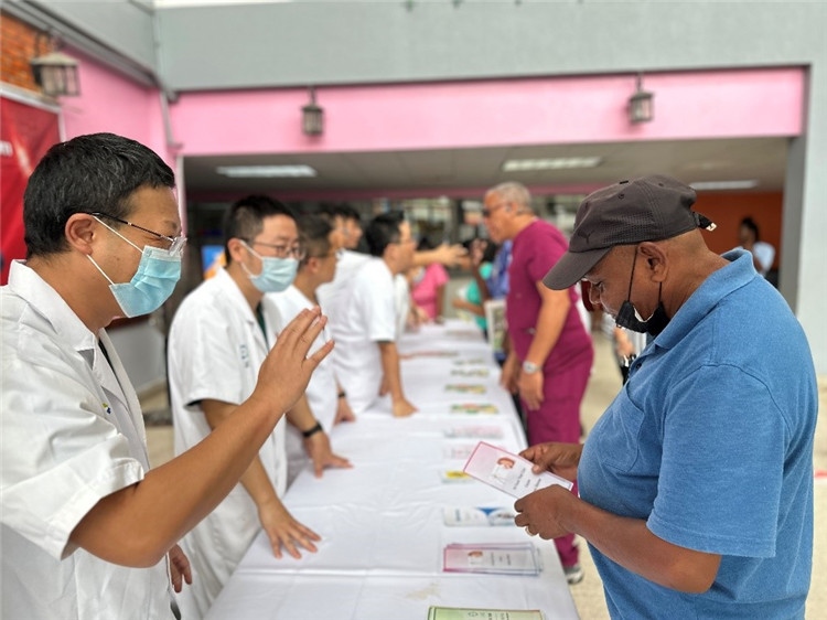 援圭醫(yī)療隊隊員們在啟動儀式上為當?shù)孛癖姺职l(fā)宣傳手冊。中國援助圭亞那醫(yī)療隊供圖