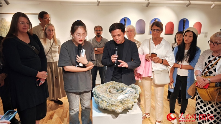 參展人、景德鎮(zhèn)陶瓷大學(xué)設(shè)計(jì)藝術(shù)學(xué)院副院長(zhǎng)余劍峰（中）向來(lái)賓介紹參展作品。人民網(wǎng)記者 殷淼攝