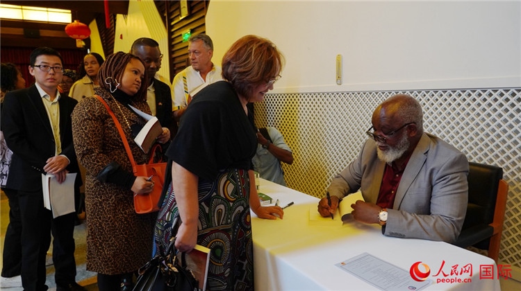 譚哲理在活動(dòng)現(xiàn)場簽名贈(zèng)書。人民網(wǎng) 劉暢攝