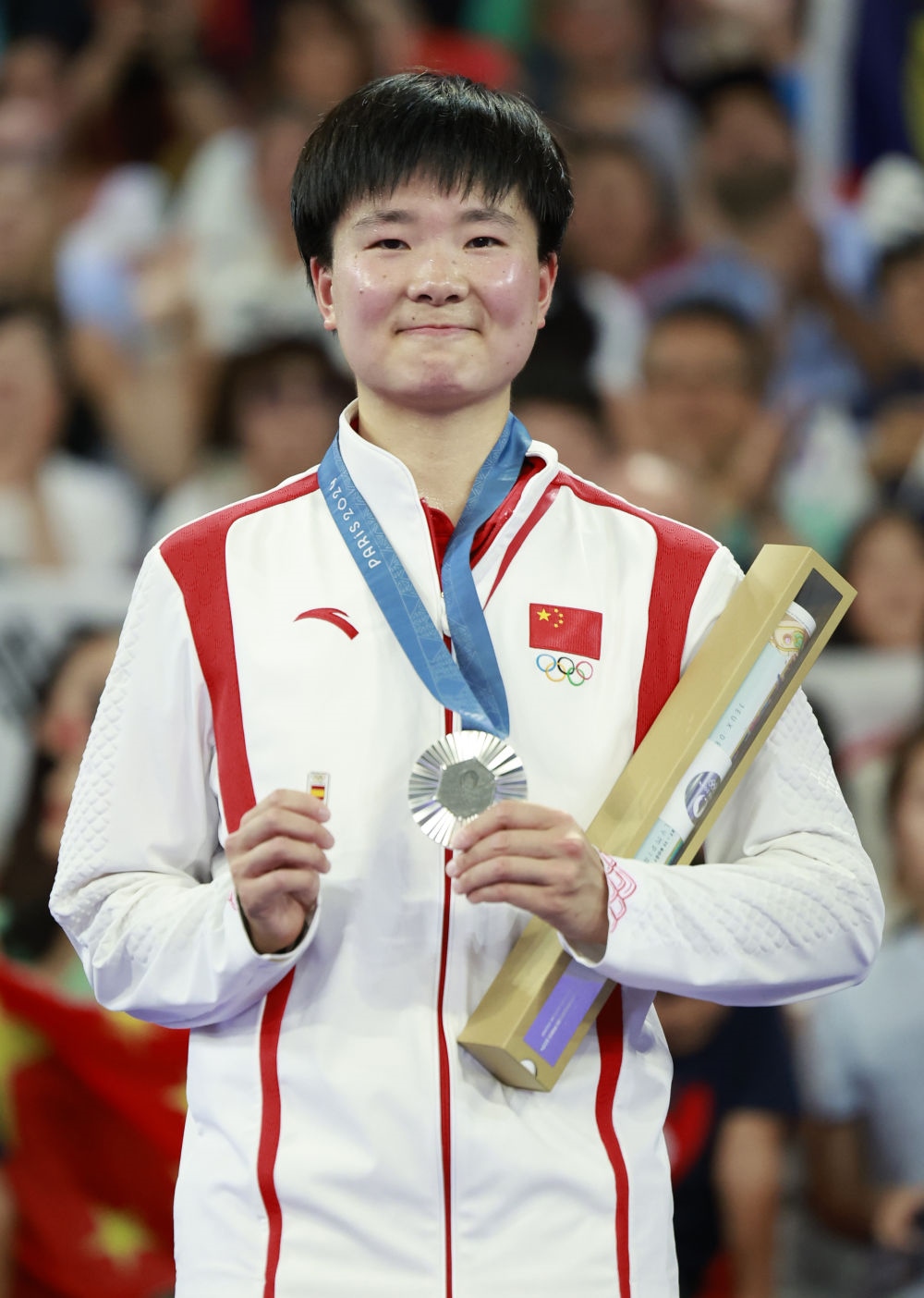 巴黎奧運會羽毛球女子單打亞軍、中國選手何冰嬌在頒獎儀式上一手握著銀牌，一手握著西班牙奧委會徽章（2024年8月5日攝）。新華社記者 任正來 攝