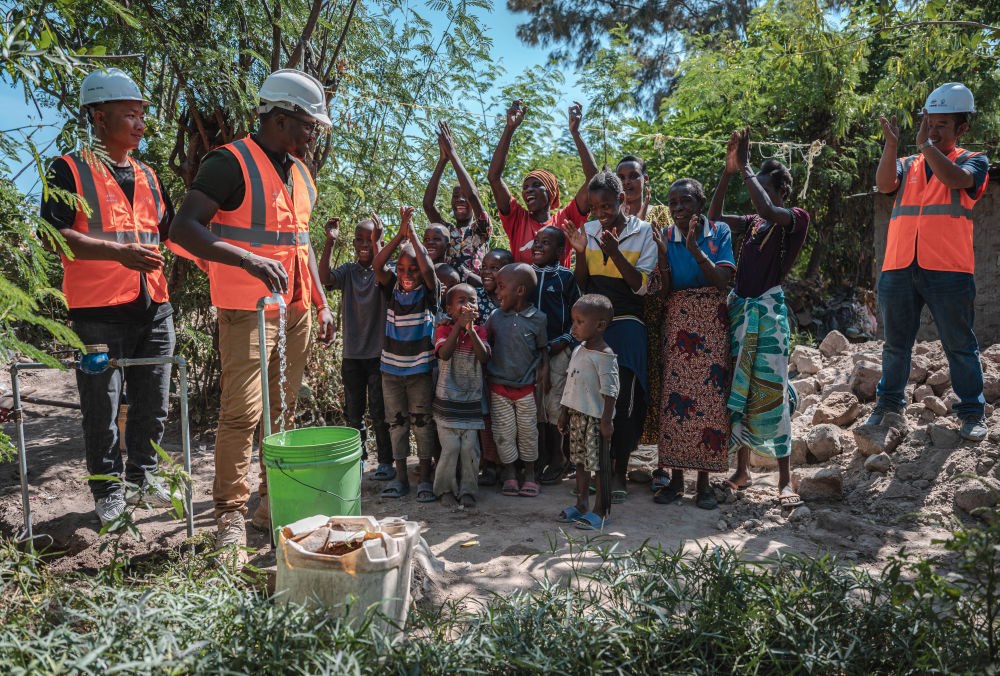 2023年6月13日，在坦桑尼亞姆萬(wàn)扎省米松圭，工作人員接通水管后贏得當(dāng)?shù)鼐用窆恼茪g呼。新華社記者 王冠森 攝