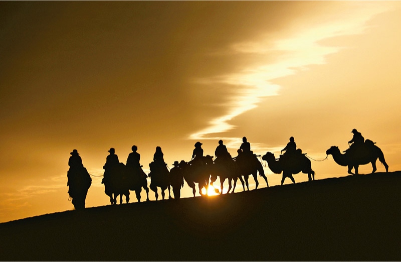 新時代以來，文化和旅游深度融合發(fā)展體制機制不斷健全，成功走出了一條獨具特色的中國旅游發(fā)展之路。圖為2024年9月1日清晨，游客在甘肅省敦煌市鳴沙山月牙泉景區(qū)乘騎駱駝，欣賞大漠風(fēng)光，體驗絲路風(fēng)情。 新華社發(fā) 張曉亮/攝