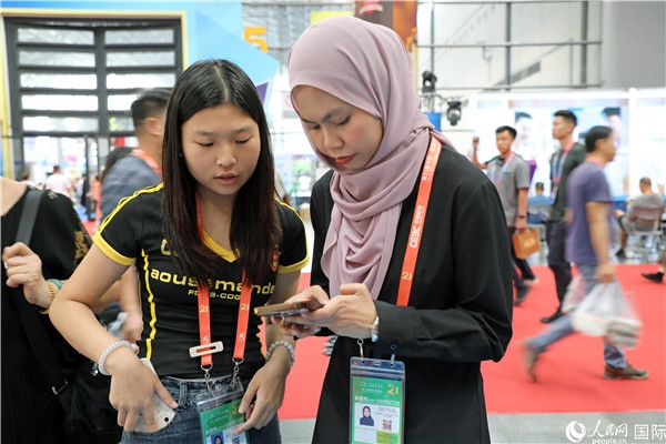 東博會現(xiàn)場，馬來西亞展商在同中方工作人員交談。人民網(wǎng)記者 趙益普攝