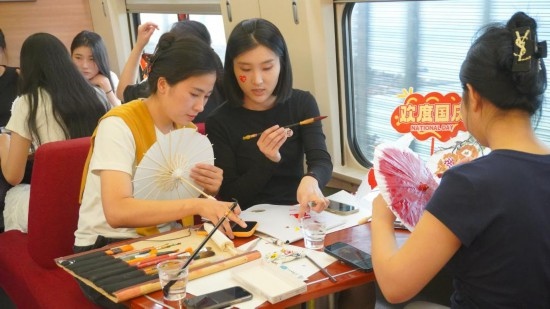 10月1日，旅客們在G1634次列車上給油紙傘作畫。新華社記者周義 攝