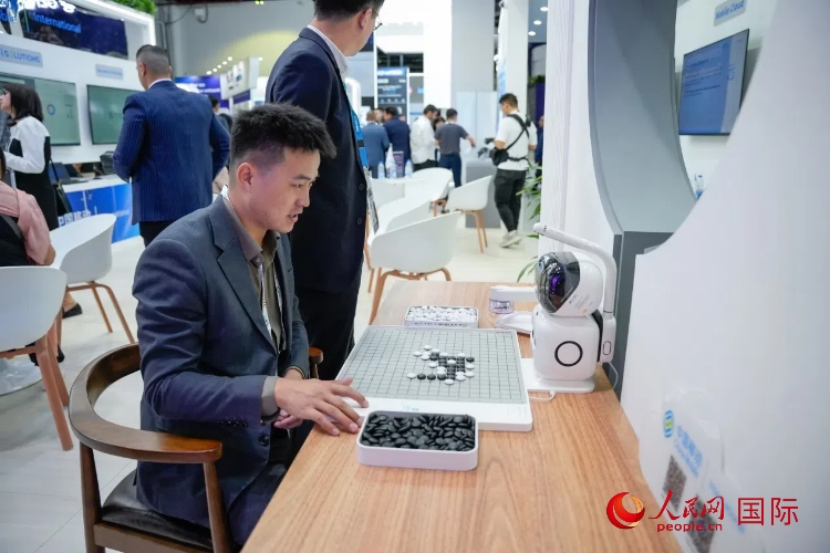 觀眾在中國(guó)移動(dòng)國(guó)際有限公司展臺(tái)體驗(yàn)智慧圍棋機(jī)器人。人民網(wǎng) 塔里克·易卜拉欣攝