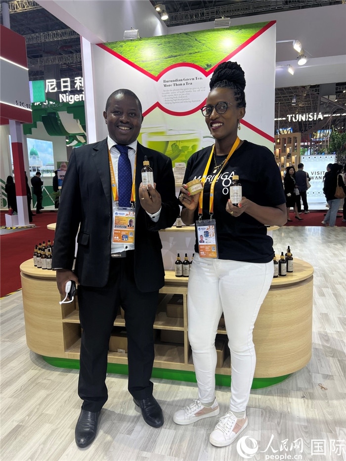 6月6日，布隆迪駐華大使館一等參贊布利馬索·阿爾弗雷德 (左，Bulimaso Alfred) 和參展商卡馬里扎·埃斯特拉 (Kamariza Estella) 在第七屆中國國際進(jìn)口博覽會(huì)布隆迪館展示當(dāng)?shù)厣a(chǎn)的辣木油。（人民網(wǎng) 艾里士 攝）
