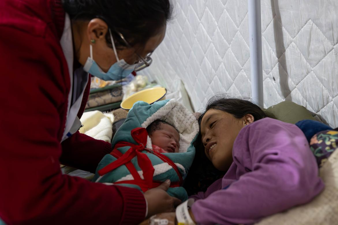 1月10日，定日縣中心醫(yī)院的婦產科醫(yī)生悉心照看一位母親和她懷里的新生兒。人民日報記者張武軍攝