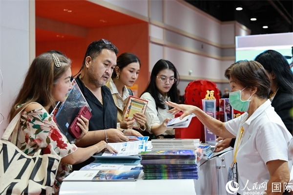 外國(guó)觀眾在中國(guó)展臺(tái)仔細(xì)閱讀赴華旅游介紹，向工作人員咨詢關(guān)于中國(guó)美食和景點(diǎn)的詳細(xì)信息。人民網(wǎng)記者 白元琪攝