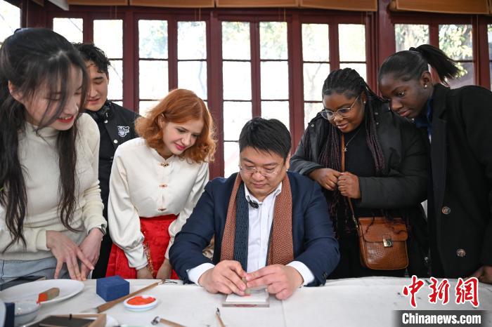 1月20日，篆刻家王臻向外籍留學生展示篆刻印章。當日，來自巴西、馬來西亞、加納、哈薩克斯坦的外籍留學生在浙江杭州西泠印社體驗福貼、春聯(lián)和篆刻，感受古老的中國傳統(tǒng)文化。中新社記者 王剛 攝