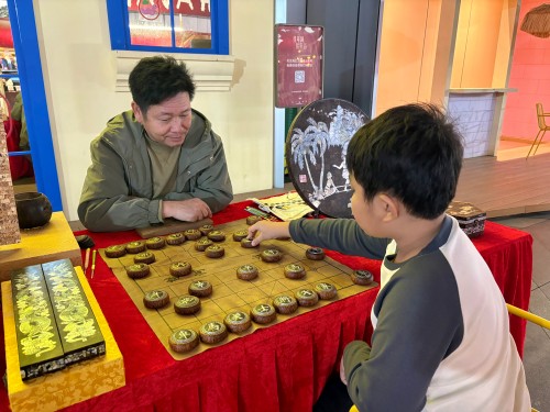 柯秋楓與市民下椰雕象棋。人民網(wǎng) 陳葉欣攝