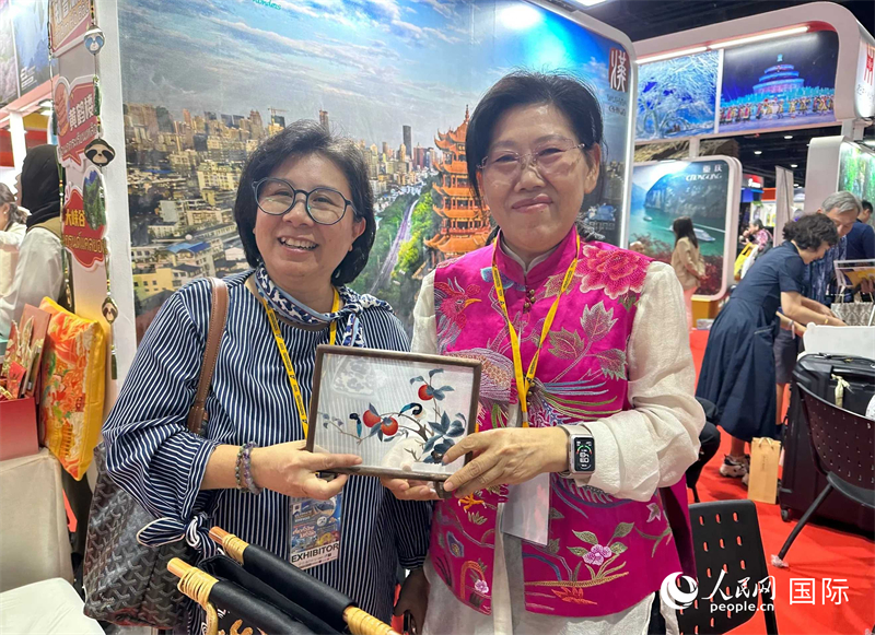 中國“大冶刺繡”傳承人劉小紅（右）參加泰國國際旅游展，向觀眾介紹中國非遺刺繡針法。人民網(wǎng)記者 簡承淵攝