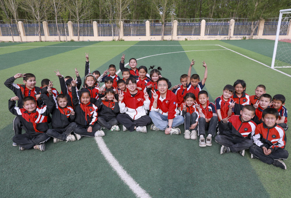 4月23日，在新疆克州阿圖什市哈拉峻鄉(xiāng)謝依特小學(xué)，支教教師王俊文（中左）、李軻凡（中右）和學(xué)生在一起。