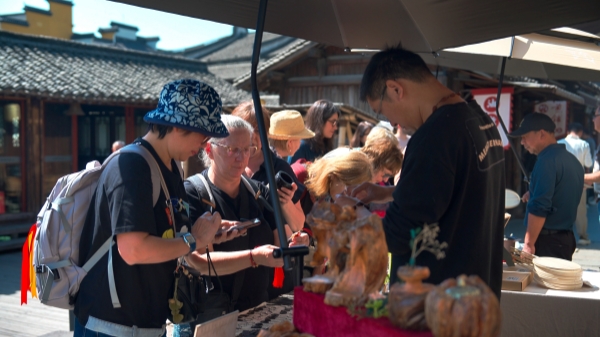 “五一”期間，游客正在烏鎮(zhèn)“水鄉(xiāng)碼頭”挑選購買文創(chuàng)產(chǎn)品。受訪者供圖